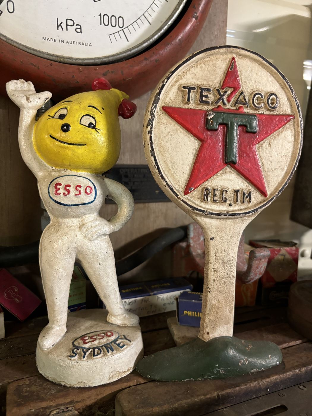 Esso Sydney oil drop man and Texaco star cast iron doorstops under a pressure gauge
